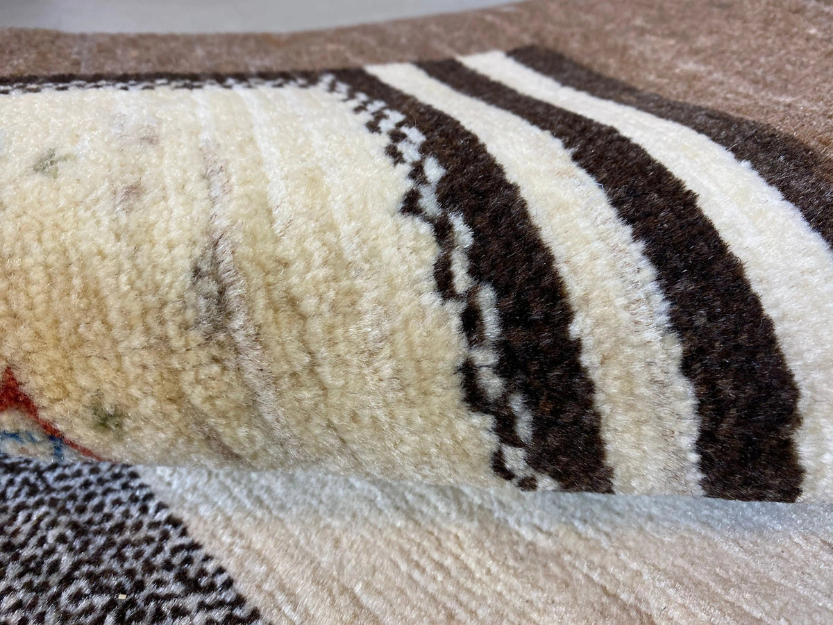 Gabbeh rug close-up: dense pile in brown and beige with dark stripes