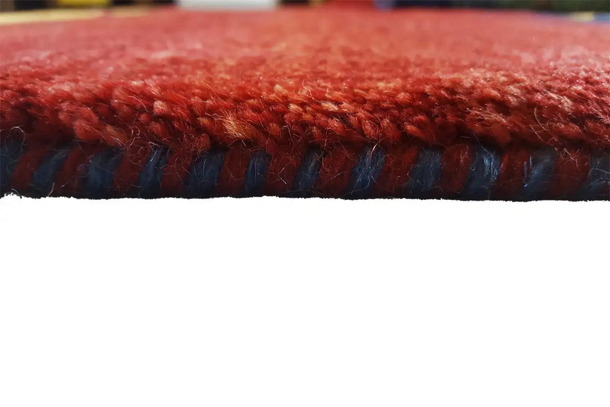 Gabbeh rug edge details: red pile with a blue fringe border