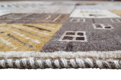 Gabbeh rug edge with fringes and beige pile, gray-brown shading along the edge.