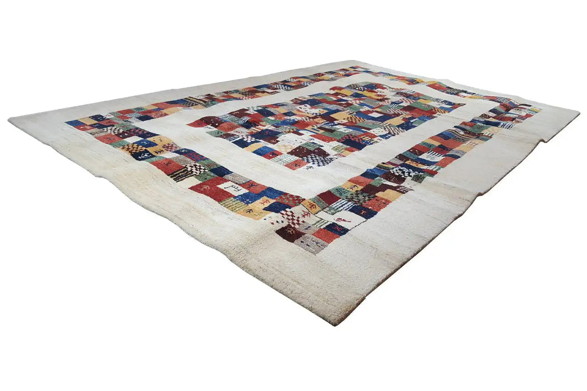 Gabbeh rug at an angle with a geometric patchwork pattern in shades of blue, red, and beige