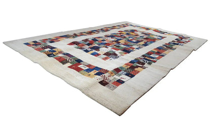 Gabbeh rug at an angle with a geometric patchwork pattern in shades of blue, red, and beige