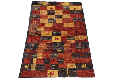 Gabbeh rug with red, beige, and gray patchwork on a dark background