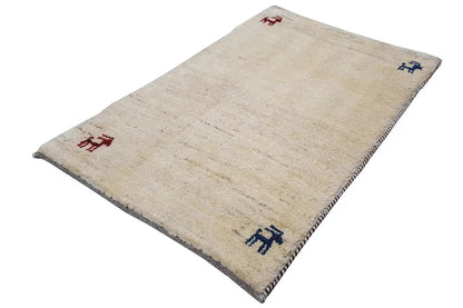 Gabbeh rug 86x56 cm, beige rug with blue and red animal motifs, diagonal view