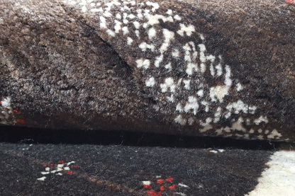 Detail of the Gabbeh rug: dark pile surface with a contrasting white pattern and subtle color accents.