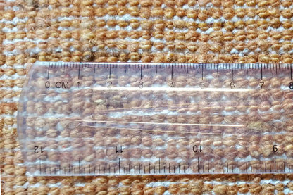 Gabbeh rug in gold, detail with measuring tape and woven pattern structure