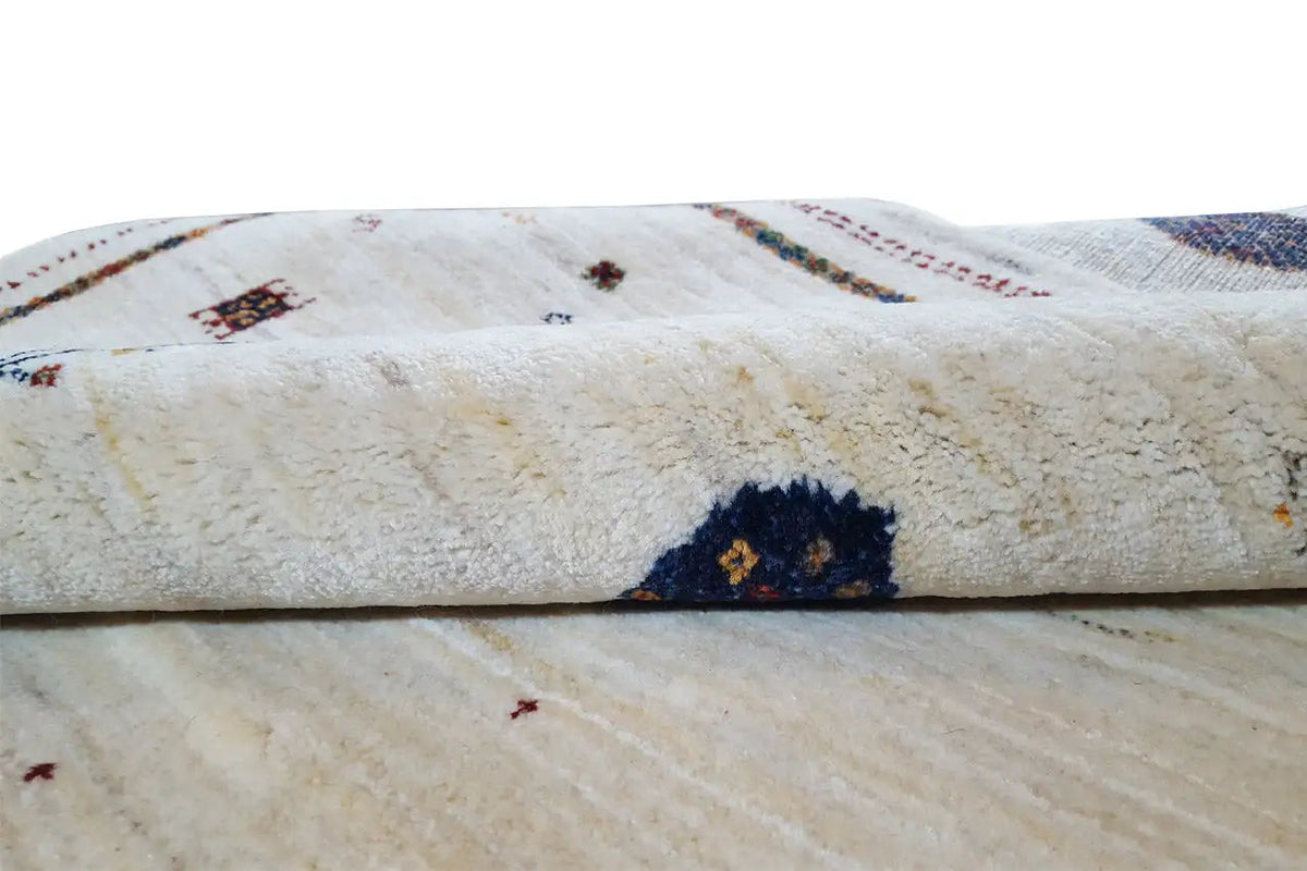 Gabbeh rug detail: pile folds with colorful motifs and a visible selvedge edge