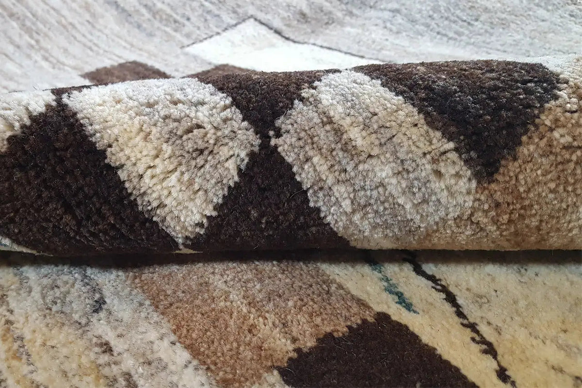 Close-up of the pile of a Gabbeh rug: short, dense wool fibers in beige and dark brown
