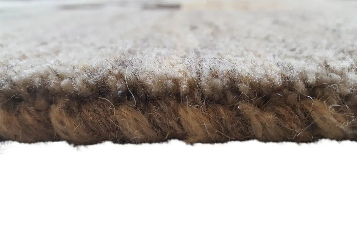 Carpet edge in detail: dense, slightly plush pile in light beige with brown tones