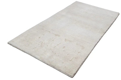 Beige rectangular rug, laid diagonally, with subtle color shading