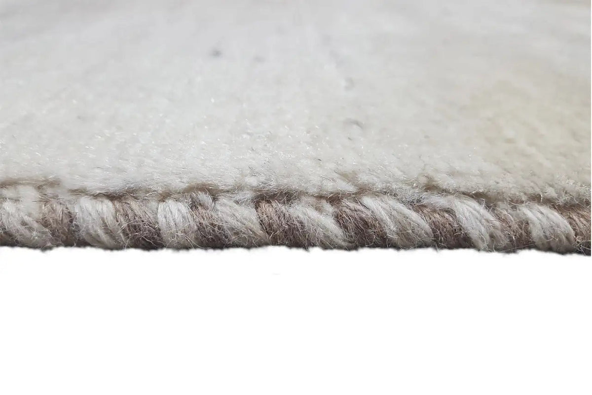 Close-up: carpet fringe along the edge, gray-beige pile.