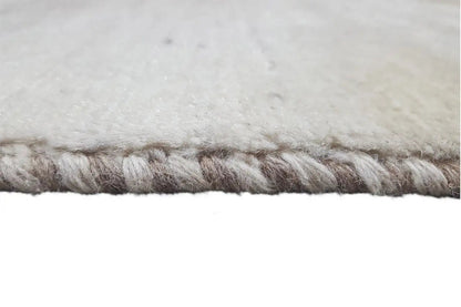 Close-up: carpet fringe along the edge, gray-beige pile.