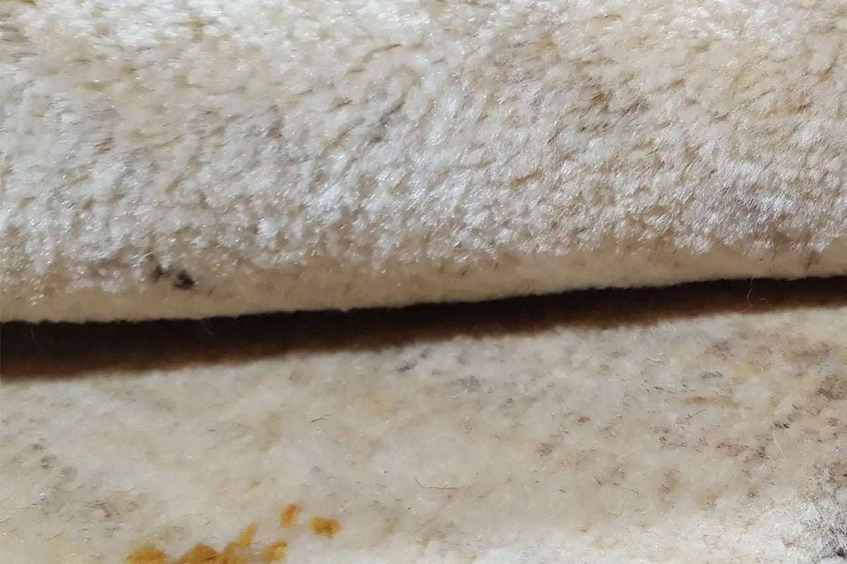Close-up: beige carpet pile with a dense texture and dark areas