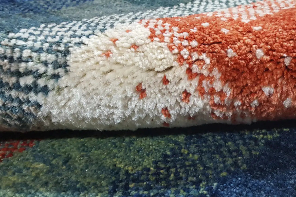 Gabbeh rug close-up: fluffy pile, blue-green with red and cream-colored areas