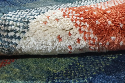Gabbeh rug close-up: fluffy pile, blue-green with red and cream-colored areas