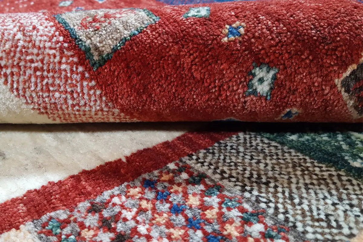 Close-up of pile and pattern: red rug with cream-colored areas and blue accents