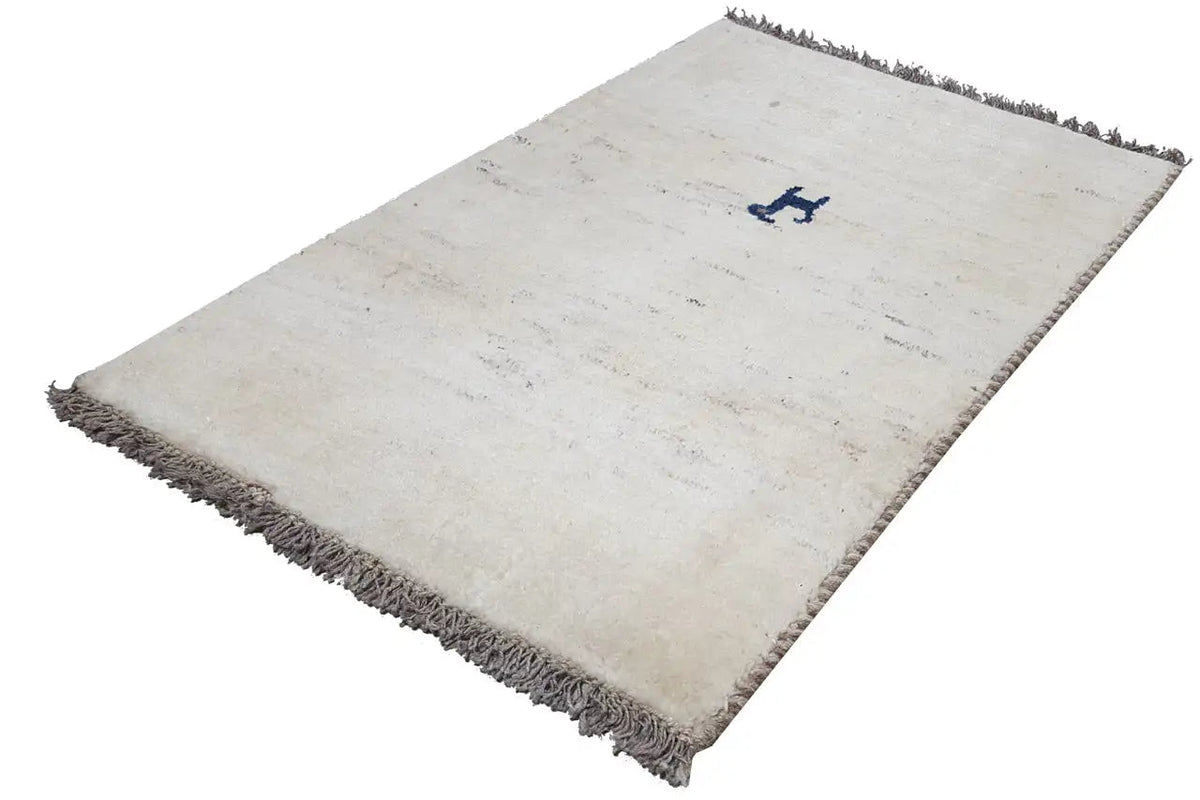 Cream-colored Gabbeh rug, laid diagonally, dark fringes, blue decorative motif