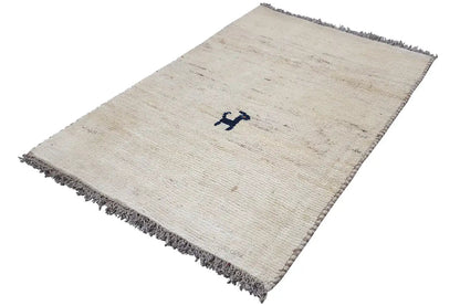 Cream-colored Gabbeh rug, diagonal, dark fringes, central blue motif