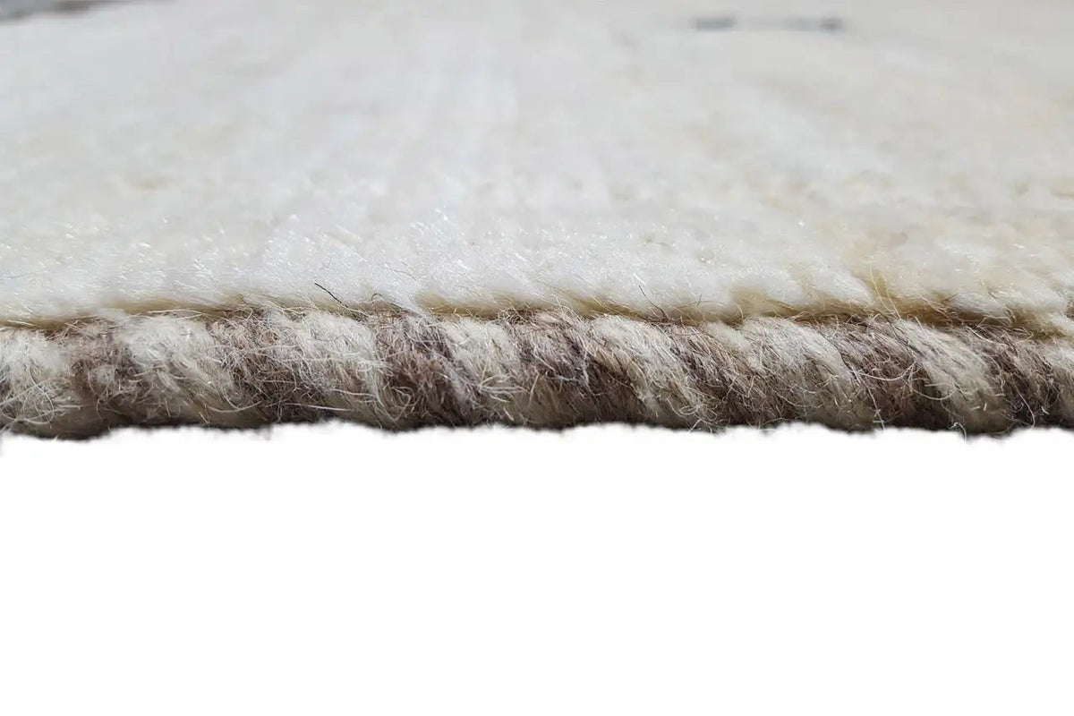 Gabbeh rug detail, cream-colored pile with dark fringe along the edge