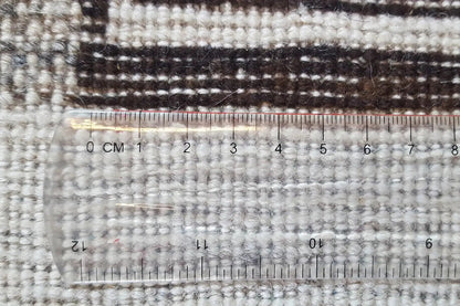 Gabbeh rug 4022 detail with measuring tape at the edge, light beige pile and dark pattern