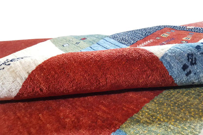 Close-up of a Gabbeh rug: red pile surface with multicolored patchwork edges