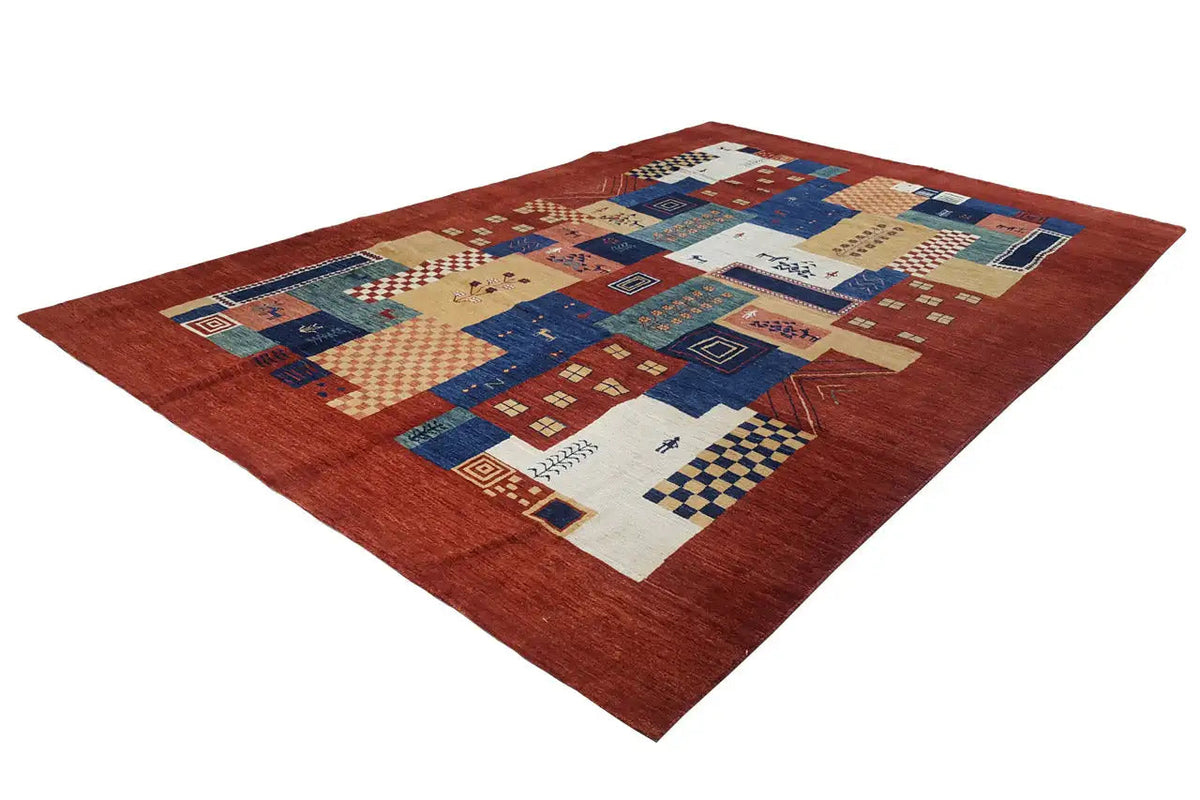 Gabbeh Lori rug (278x182 cm) viewed from a three-quarter angle, red background with a patchwork of blue and cream