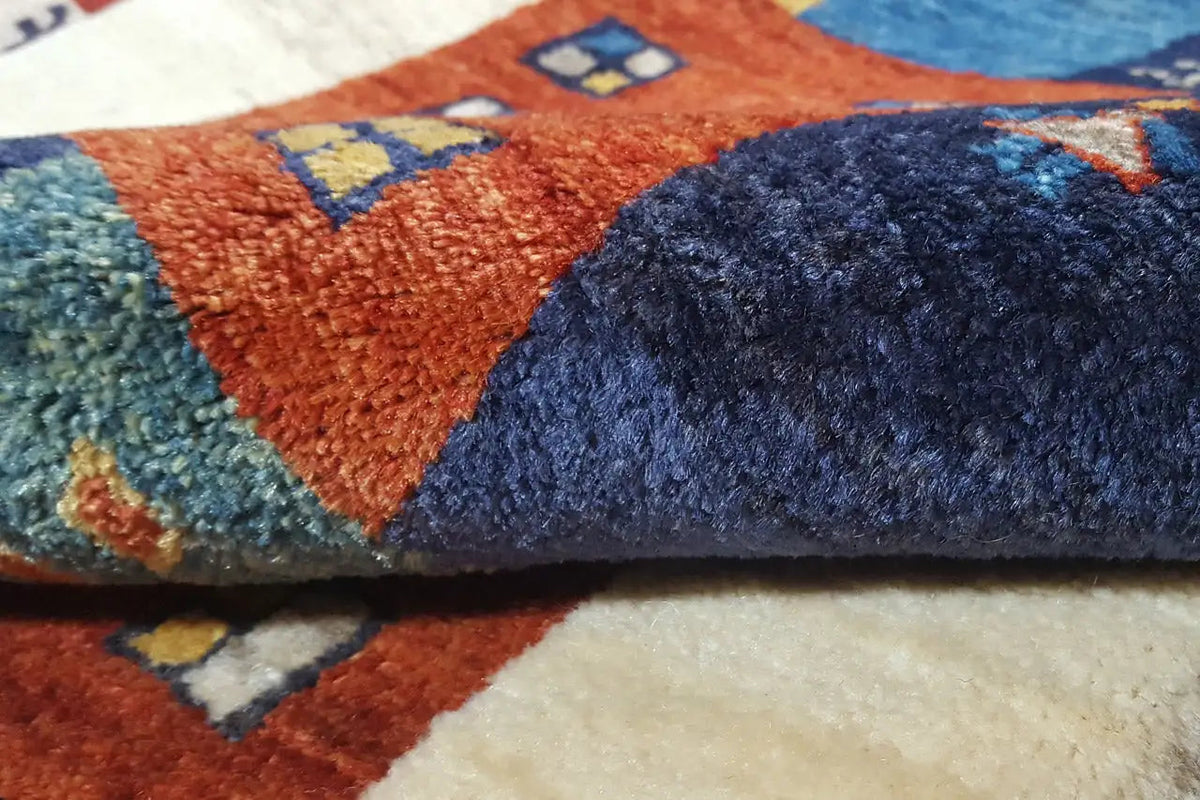 Gabbeh rug close-up: multicolored woven texture with a dark blue and orange motif
