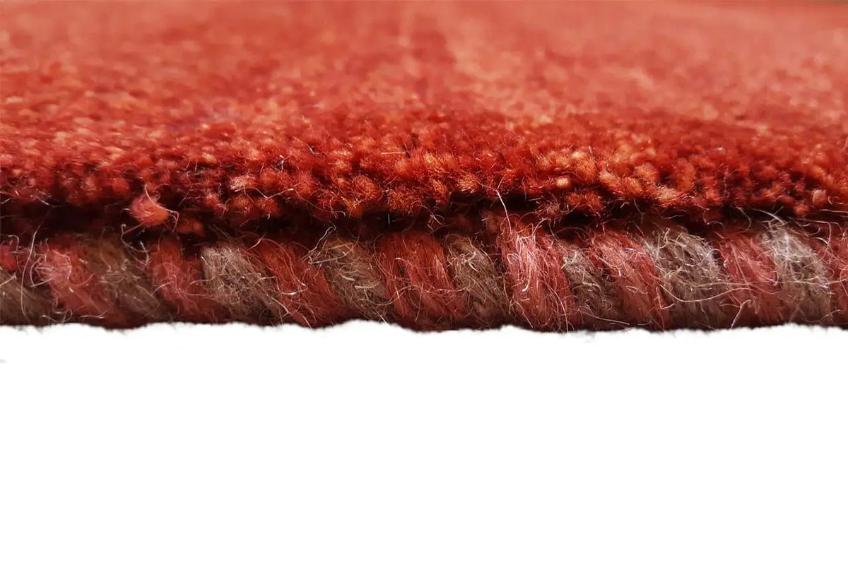 Close-up of the edge of the carpet: dense red pile with underside and edge