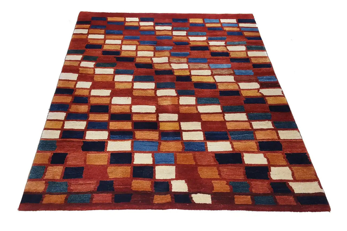 Gabbeh rug with a geometric patchwork pattern in red, blue, beige, and cream