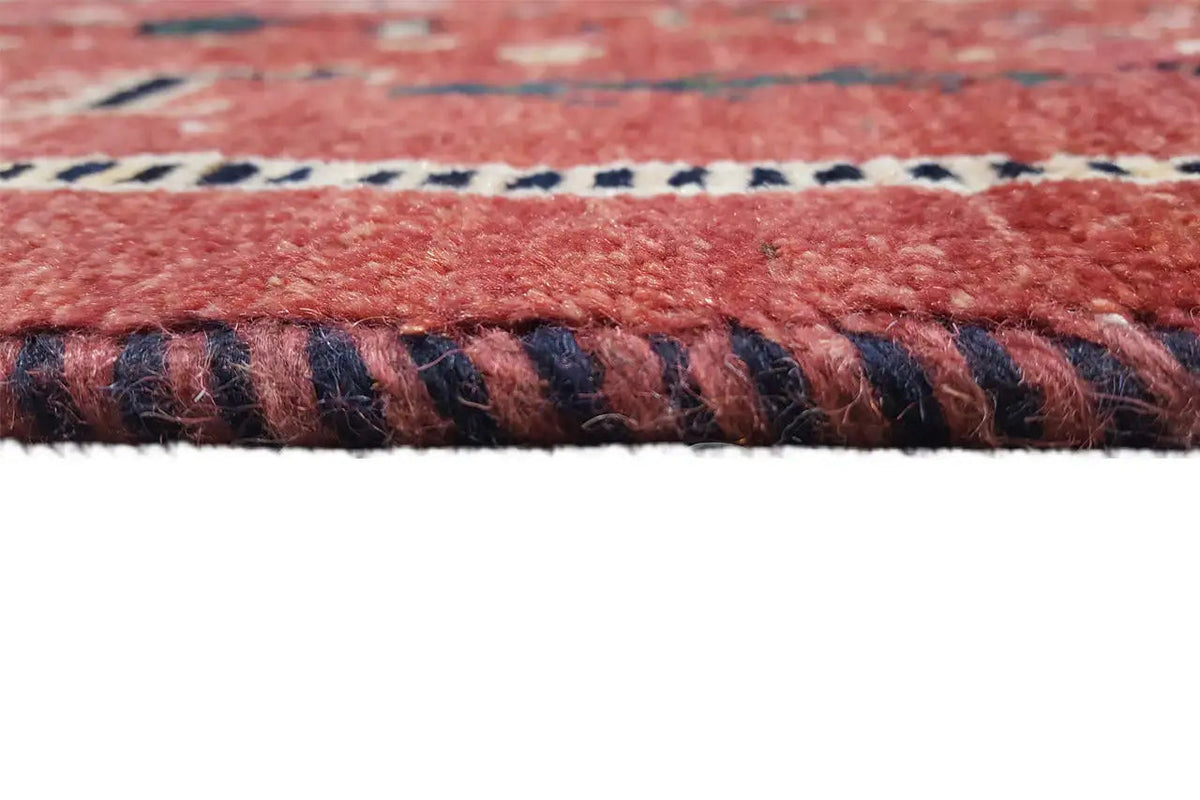 Detail of the carpet edge: reddish-brown pile with a multicolored border and fringes