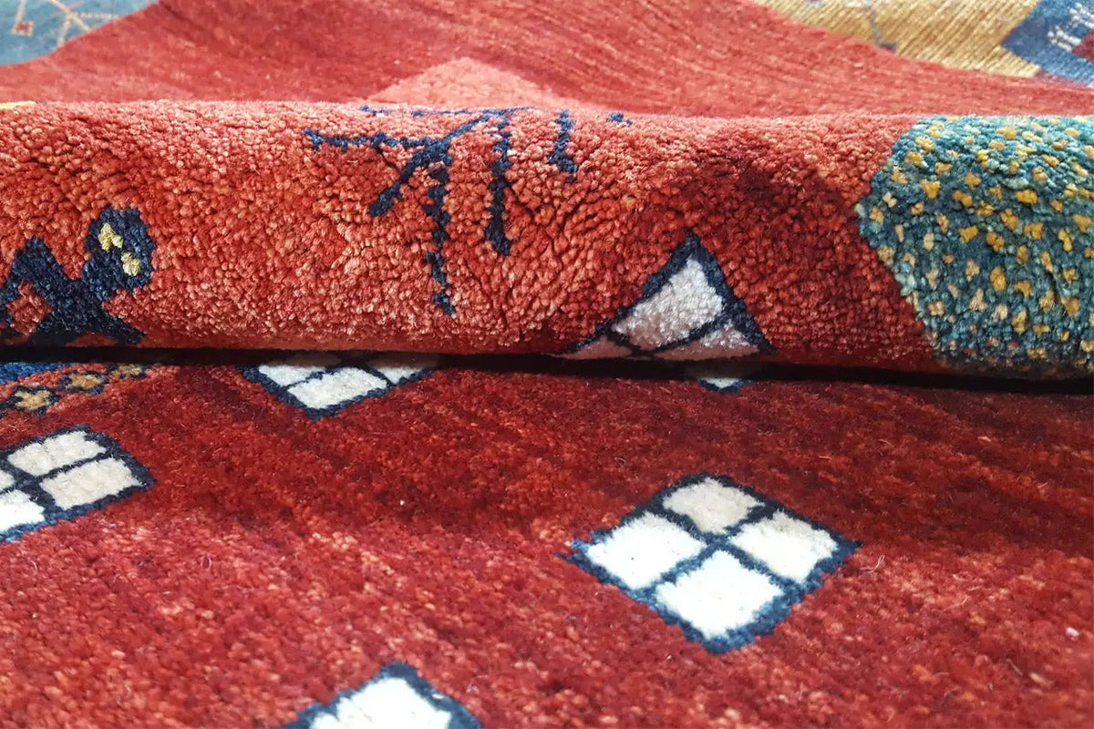 Gabbeh rug: red pile with a blue pattern and white-accented motifs