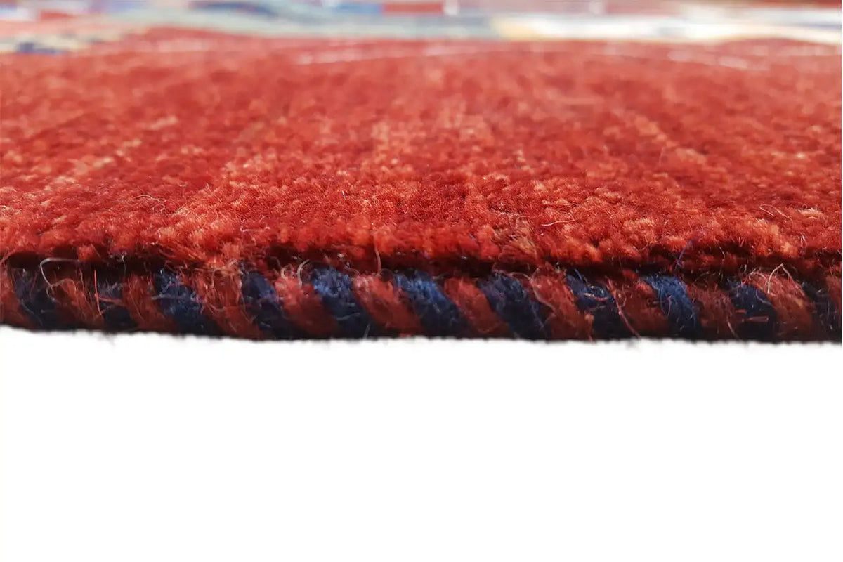 Gabbeh rug: close-up of red pile and bound edge with a dark trim
