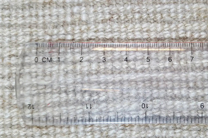 Gabbeh rug with tape measure: dense weave, beige color, low-pile texture.
