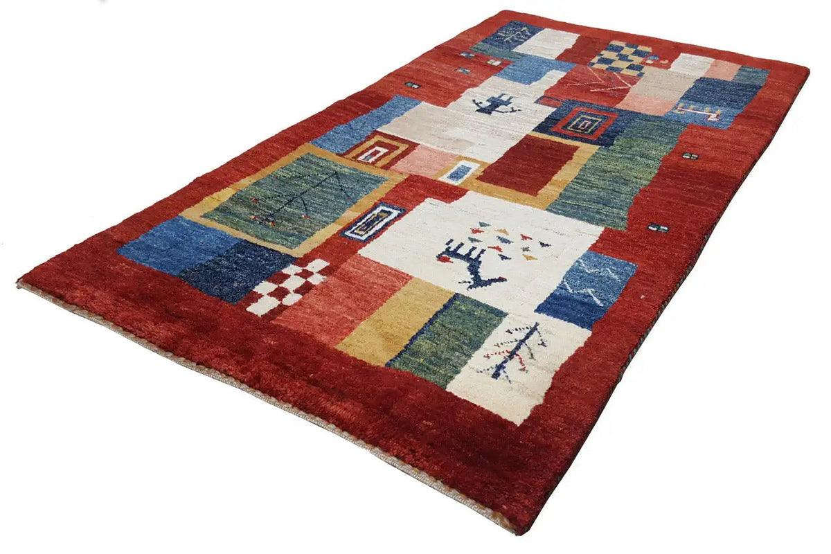 Rug with a red base and geometric sections in blue, green, and cream, angled