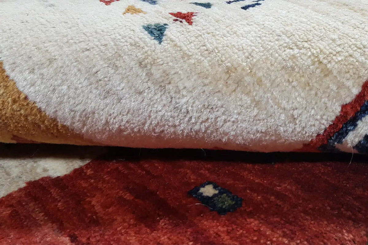 Close-up of a carpet: dense pile with a red border and multicolored patterns