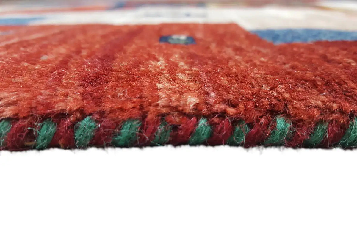 Carpet edge with dense red pile and multicolored fringes, close-up