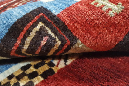 Close-up: red Gabbeh rug with a blue and black ornamental pattern
