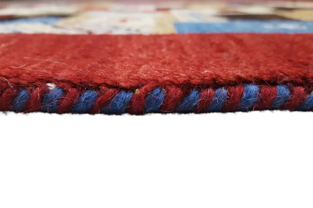 Carpet edge with fringe: red yarn and blue-accented threads