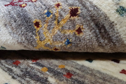 Close-up of a Gabbeh rug: colorful floral motifs on a gray, mottled background