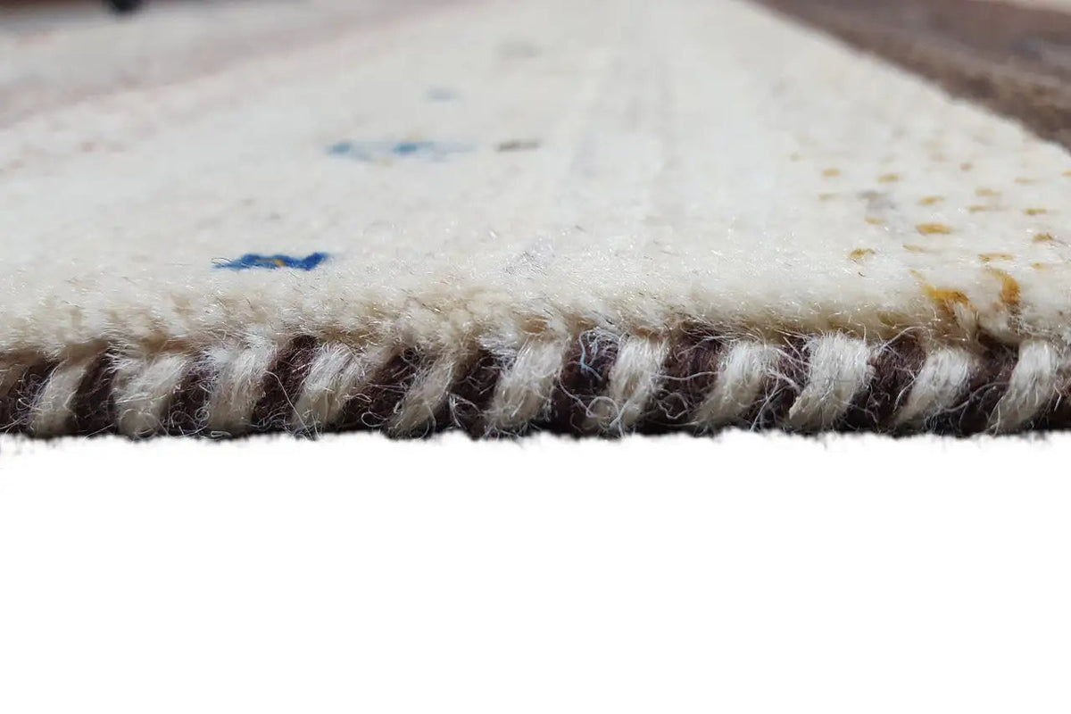 Gabbeh rug, detail of the fringes along the edge, short pile in beige and dark gray