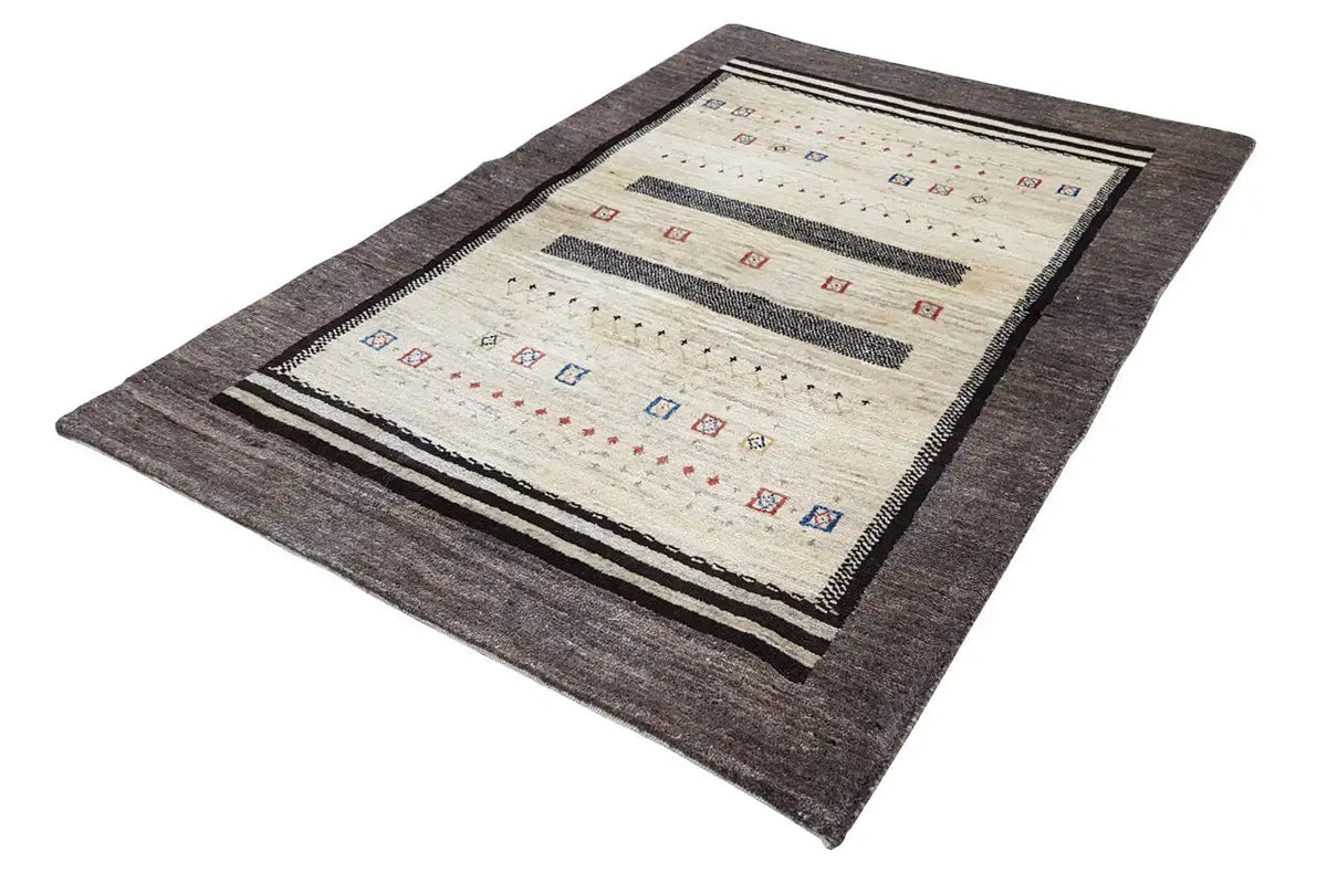 Gabbeh rug laid flat: cream-colored central area with multicolored symbols