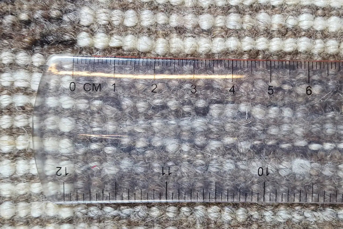 Gabbeh rug surface with measuring tape over the patterned pile