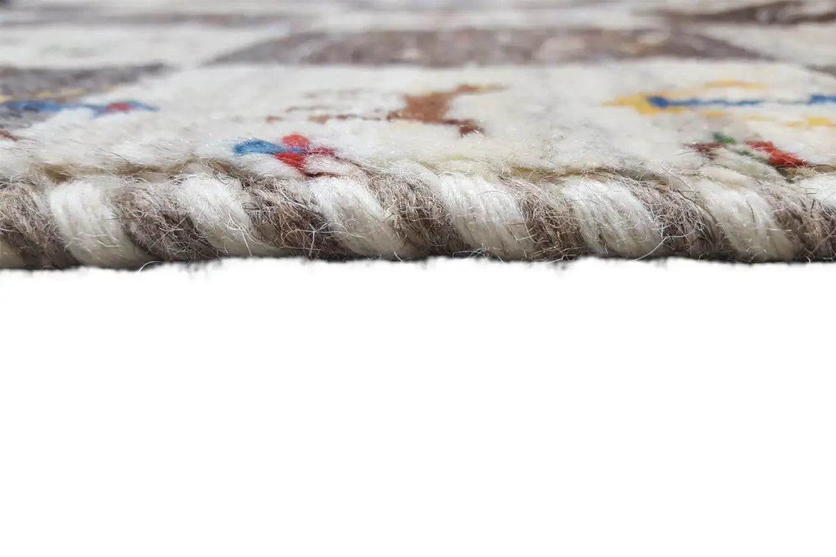 Gabbeh rug edge finish with short fringes, visible embroidered motifs in the pile