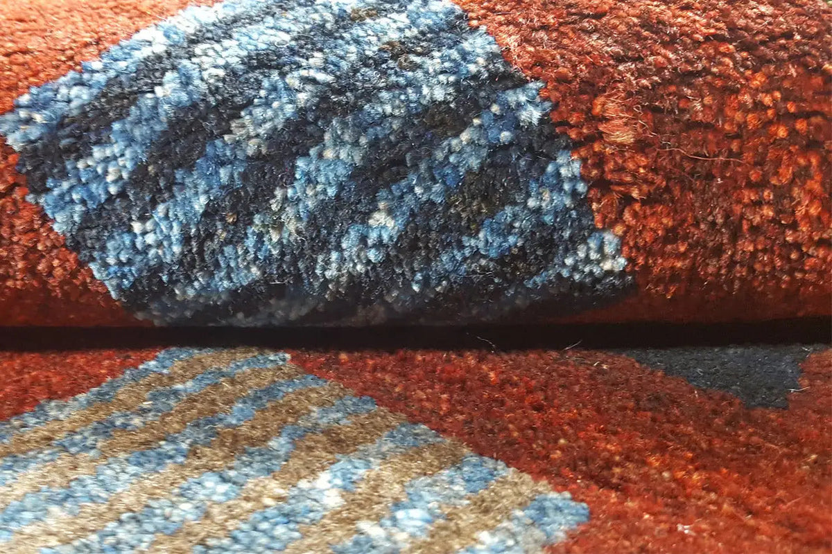 Gabbeh rug detail: reddish-brown pile with blue stripes and edging