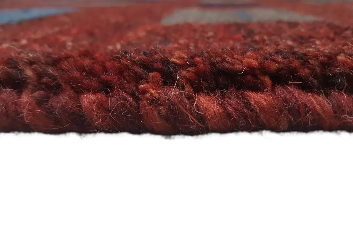 Gabbeh rug side view: dense reddish-brown pile with a cross edge