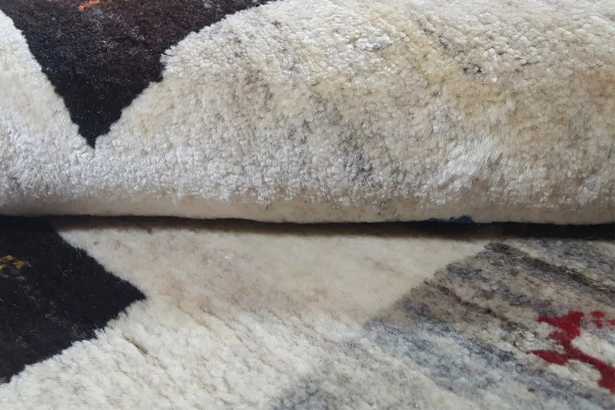 Gabbeh rug in detail: pile and cream-colored area with a dark pattern