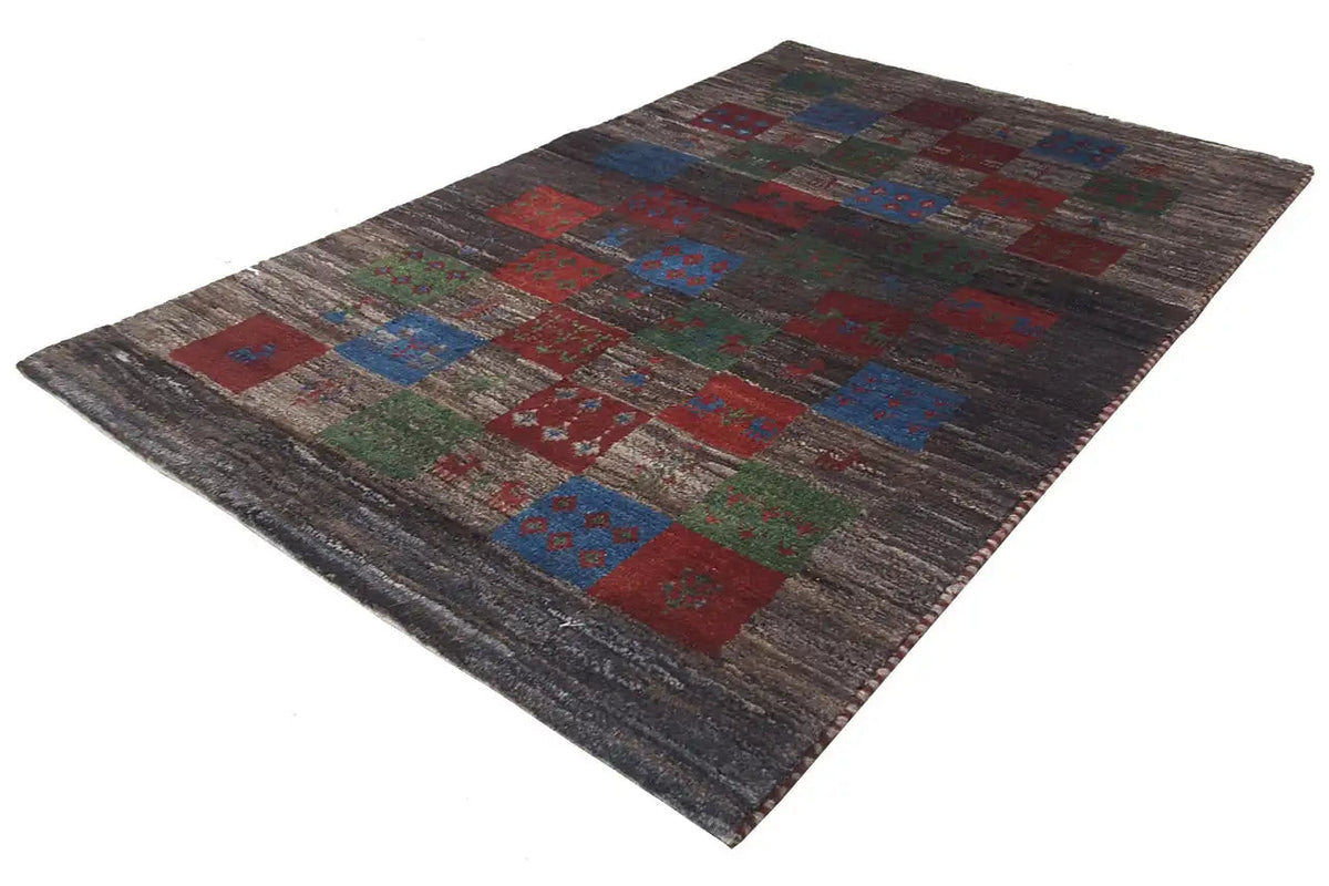 Gabbeh rug spread at an angle, patchwork ornaments in red, blue, and green on gray