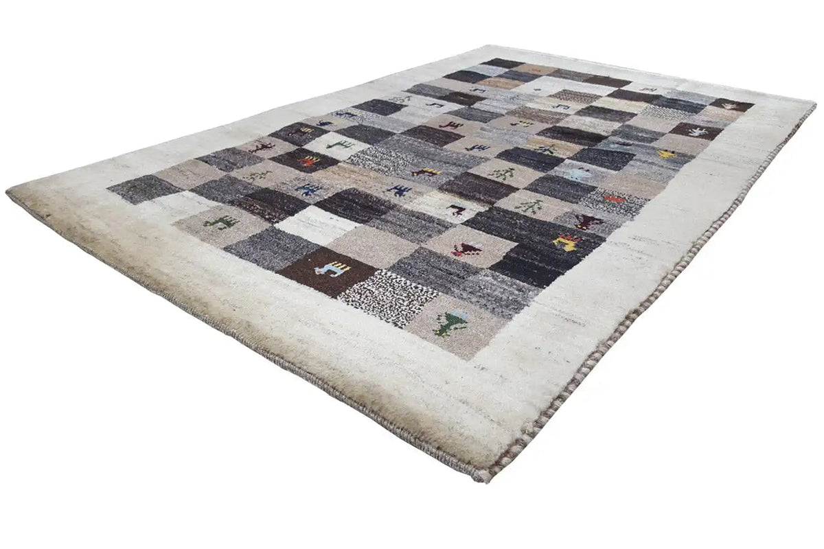 Gabbeh rug at an angle, beige background, gray and dark squares, animal motifs