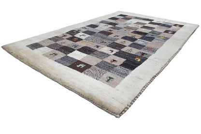 Gabbeh rug at an angle, beige background, gray and dark squares, animal motifs