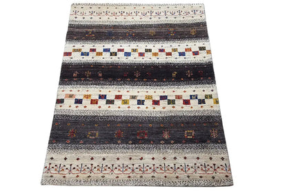 Rug in three-quarter view with a striped and diamond pattern, light beige, dark, colorful