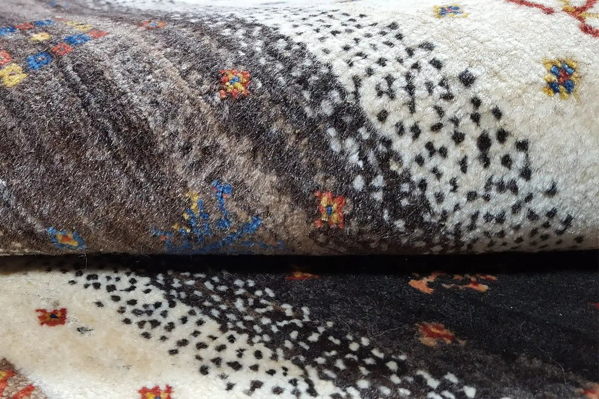 Carpet detail with dense pile and colorful ornaments in a dark striped area